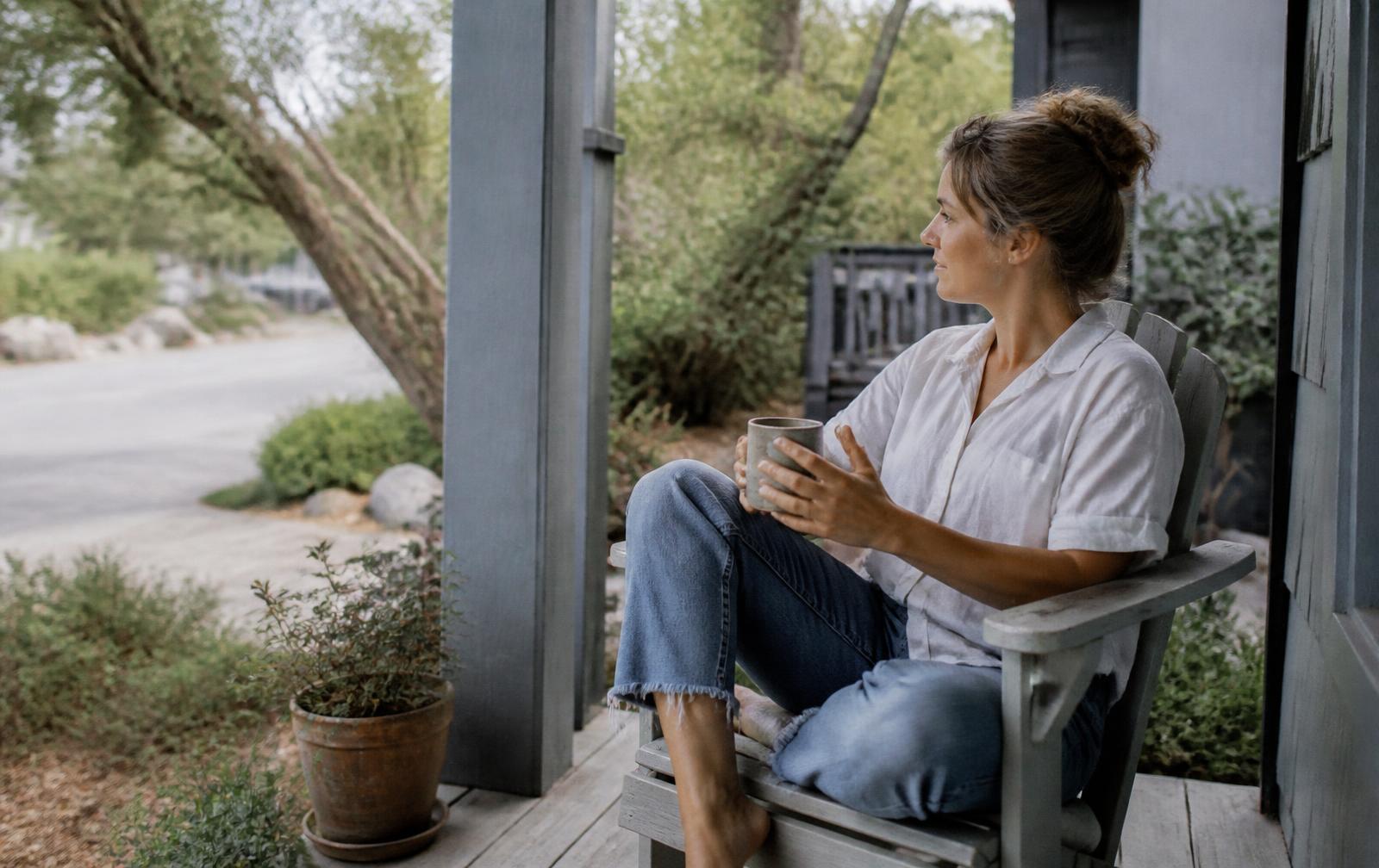 A person with a coffee on a porch on a weekday morning